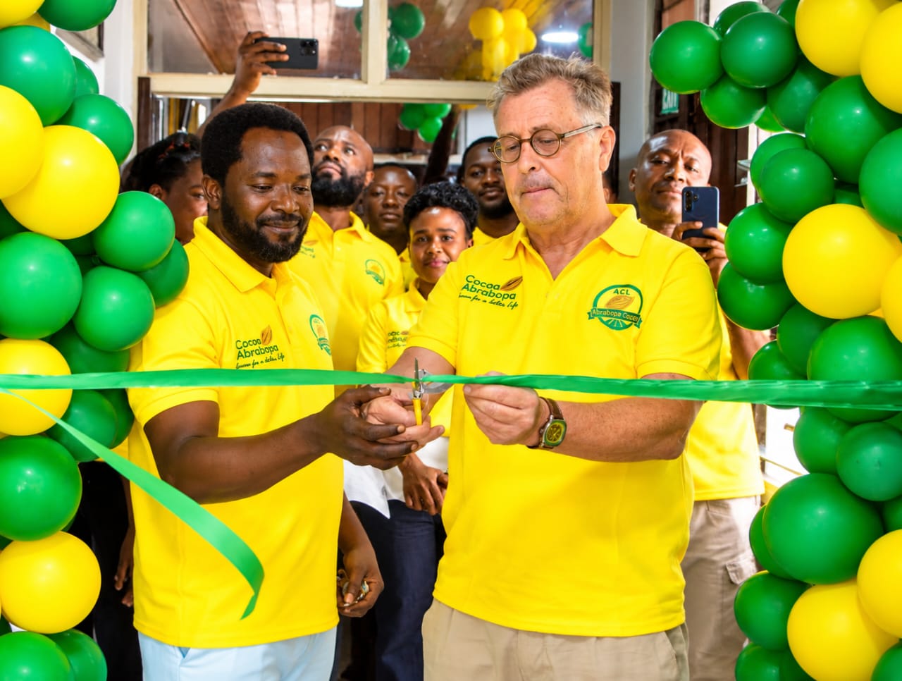 Ribbon cutting at the ACL office entrance, surrounded by colleagues and green and yellow balloons